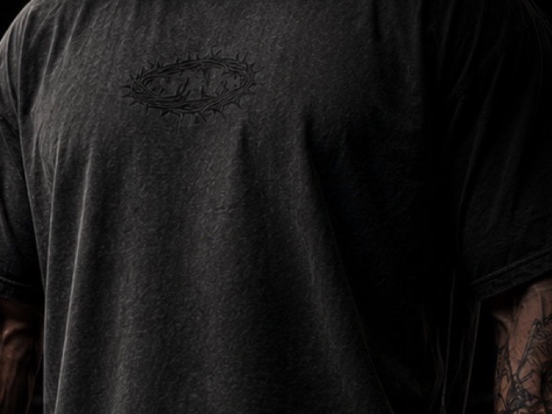 Close crop of the acid wash black Crown of Adam tee showing its washed fabric texture.